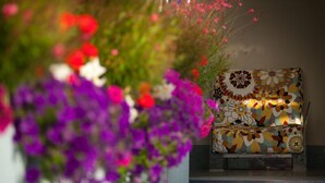 A chair with a floral pattern, surrounded by vibrant flowers. - Hotel Nina (Bibbona)