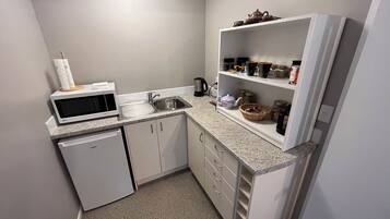 A compact kitchen with a microwave, sink, and white cabinets.
