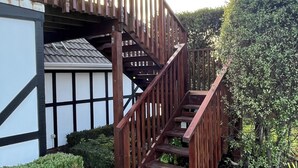 A wooden staircase leading to a house with a white and black exterior. - Tudor Manor Bed & Breakfast (Paraparaumu)