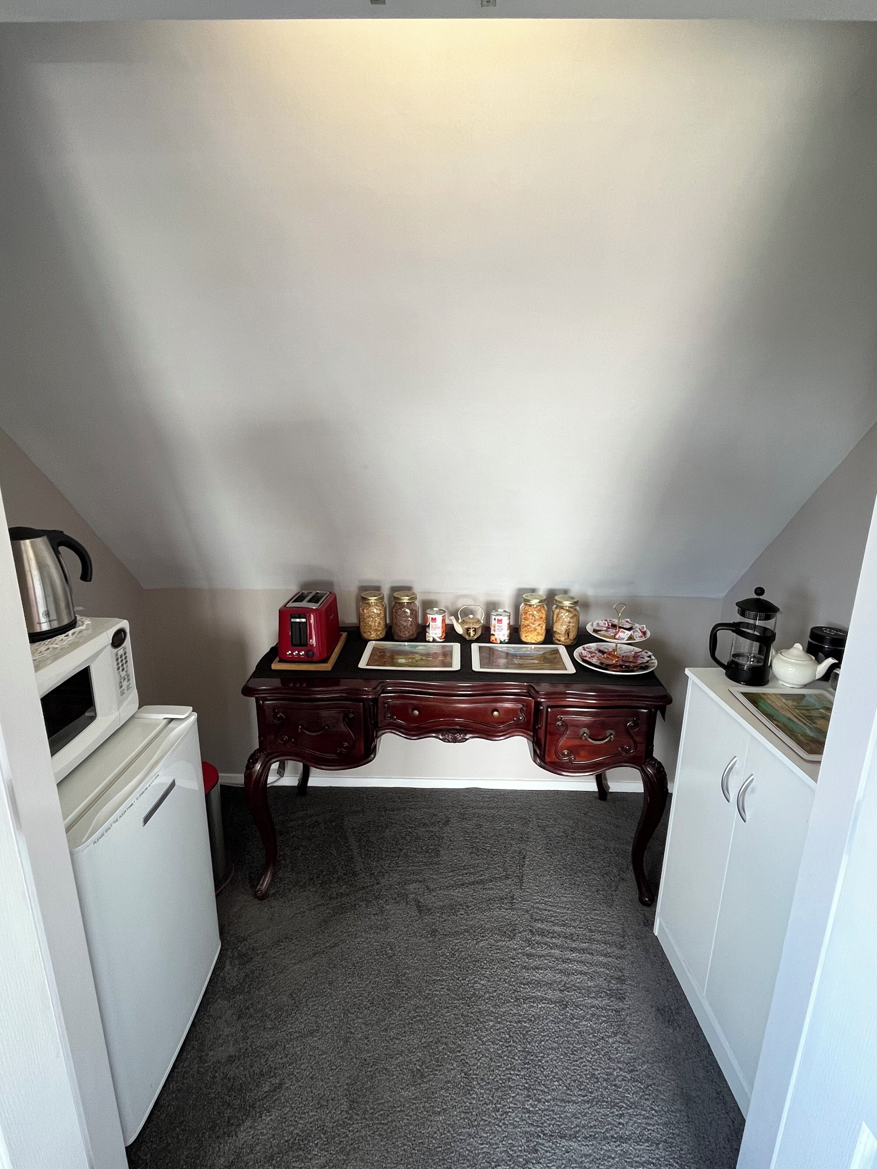 A compact kitchen with a microwave, toaster, and various jars on the counter.