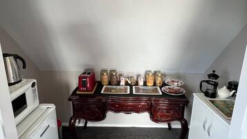 A compact kitchen with a microwave, toaster, and various jars on the counter.