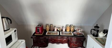 A compact kitchen with a microwave, toaster, and various jars on the counter.