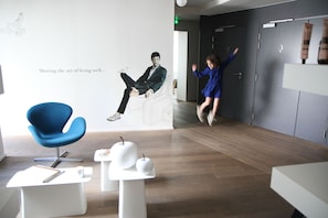 A modern interior with a blue chair, white tables, and a large wall mural.