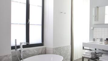 Ein modernes Badezimmer mit einer freistehenden Badewanne, einem großen Fenster und einem Waschtisch mit Spiegel.