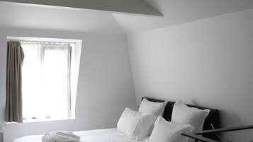 Un dormitorio con cama, ventana con cortinas, lámpara de techo y estante empotrado.