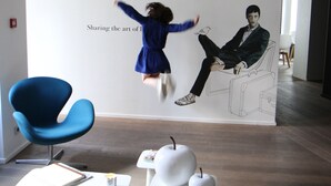 A modern interior with a blue chair, white tables, and a wall with a man and a child. - Hôtel Quatorze (Colmar)