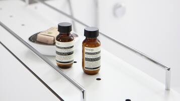 Casa de banho com banheira, chuveiro e dois frascos de produtos de higiene numa bancada.