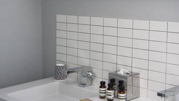 A modern bathroom with a large mirror, two sinks, and a tiled backsplash.