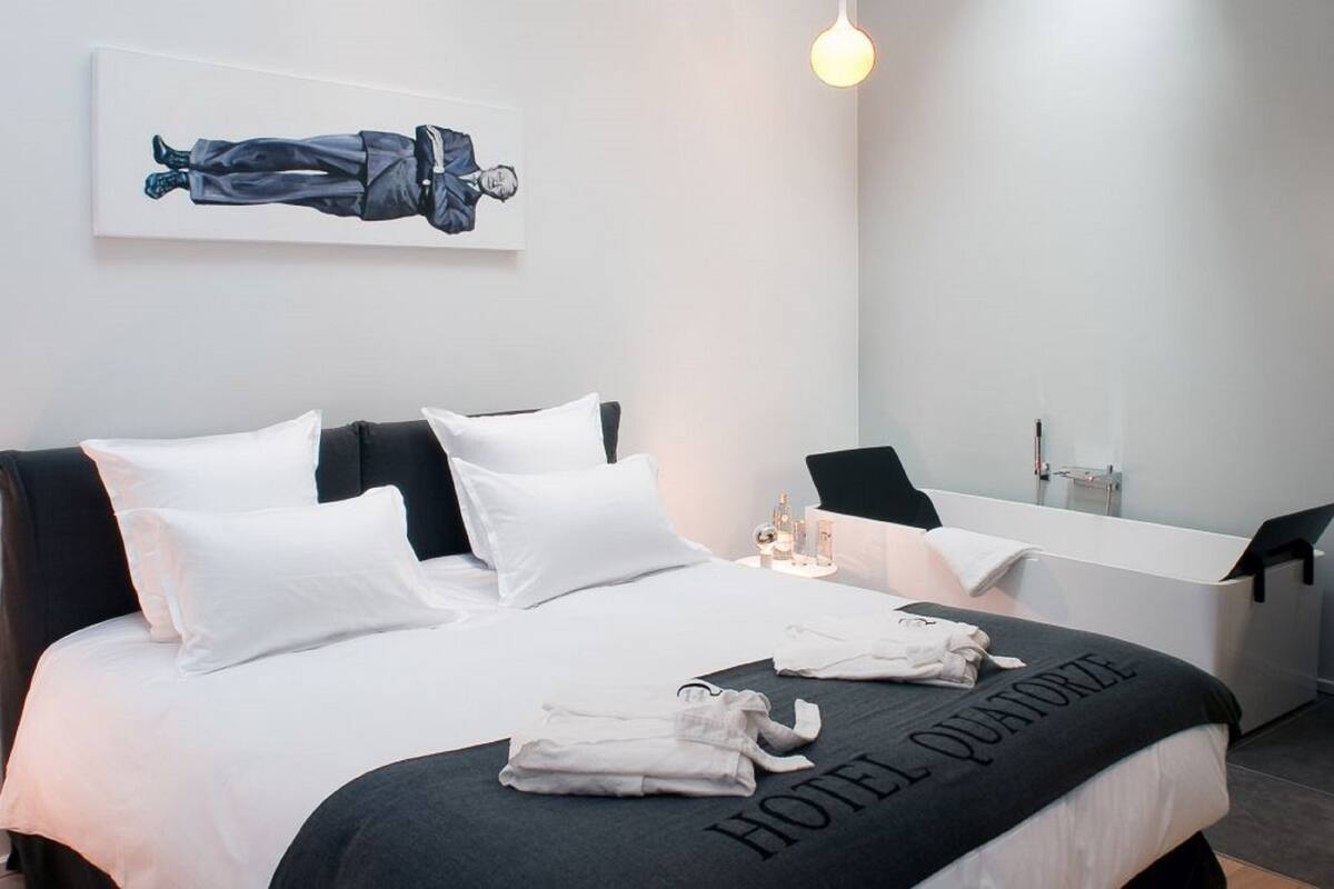 A modern hotel room with a neatly made bed, a desk, and a large window.