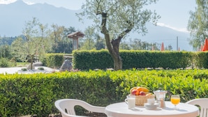 Een terras met een ontbijttafel, compleet met fruit, een melkkruik en een koffiepot.