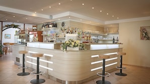 Een bar met een gebogen toonbank, meerdere stoelen en een divers assortiment flessen en glazen.