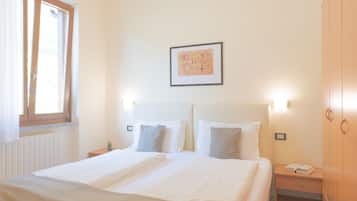 Habitación de hotel con una cama grande, mesitas de noche, un armario y un cuadro en la pared.