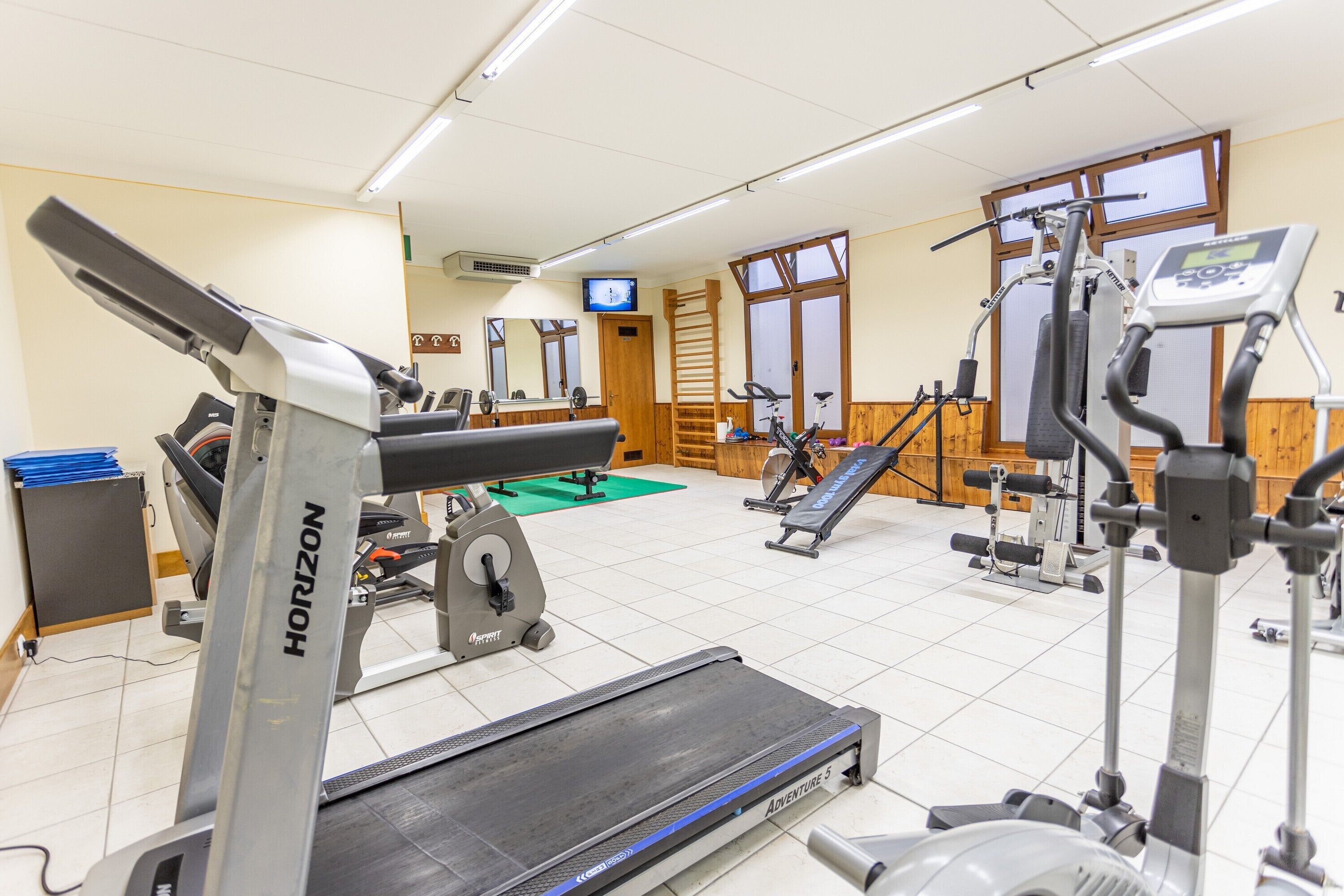 A gym with various exercise equipment including treadmills, stationary bikes, and weight machines.