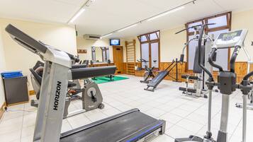 A gym with various exercise equipment including treadmills, stationary bikes, and weight machines.