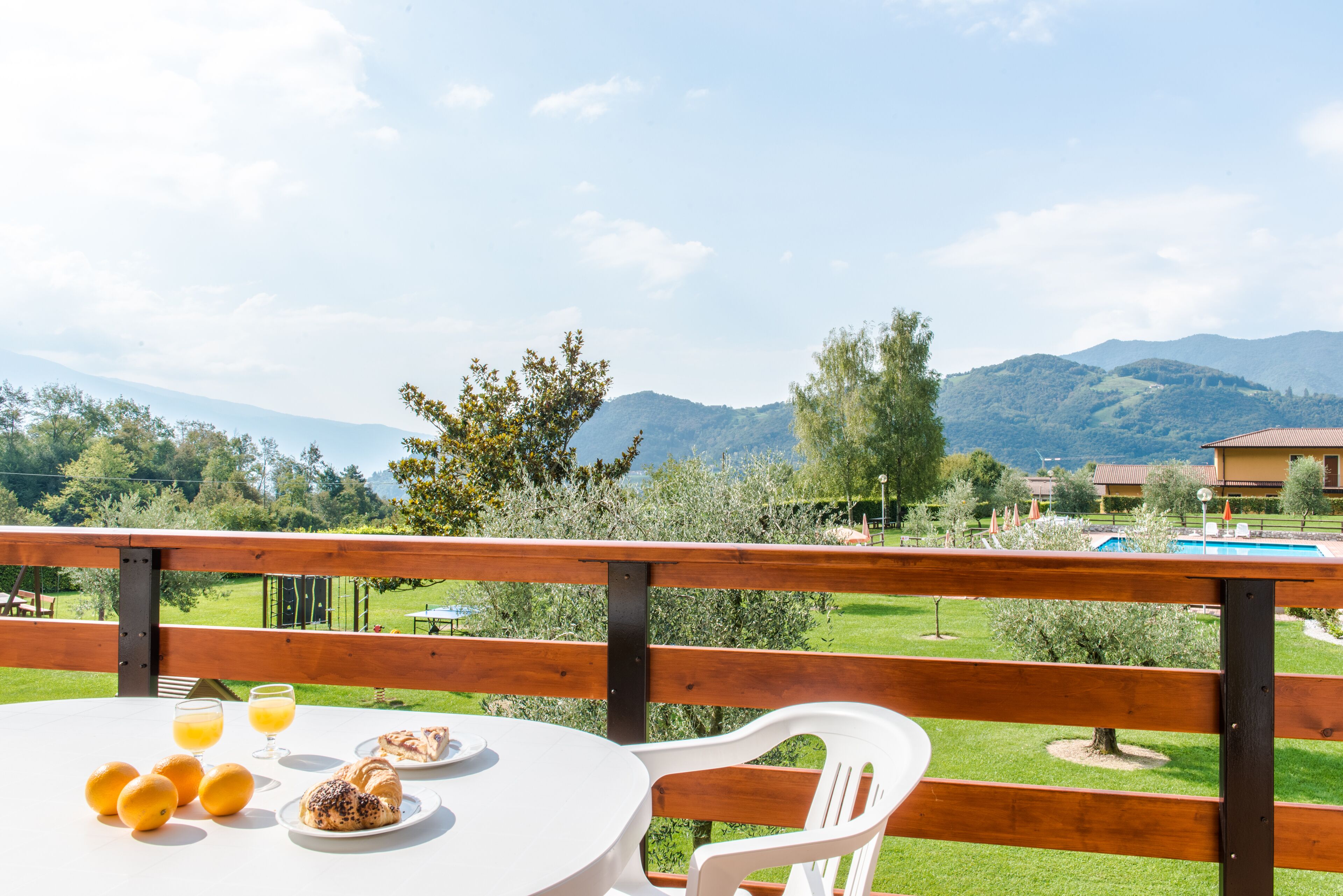 A table with breakfast items and a view of a pool and mountains.