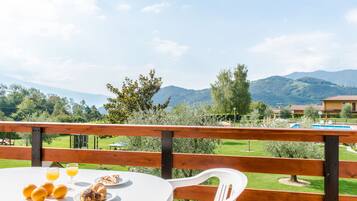 A table with breakfast items and a view of a pool and mountains.