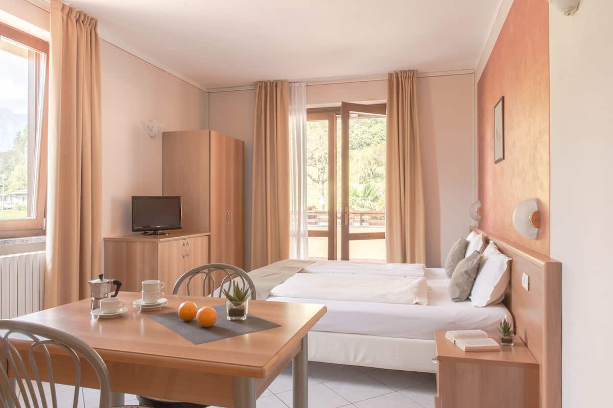 Een hotelkamer met een bed, een bureau met stoel, een televisie en een raam met gordijnen.