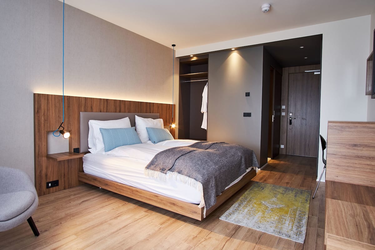 A modern bedroom with a wooden bed, bedside tables, a chair, and a walk-in closet.