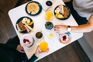 Una escena de desayuno con diversos alimentos en los platos, como tostadas, huevos y fruta.