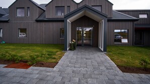 A modern building with a symmetrical facade, a central entrance with a covered walkway, and a well-maintained lawn. - Hótel Berg (Reykjanesbær)