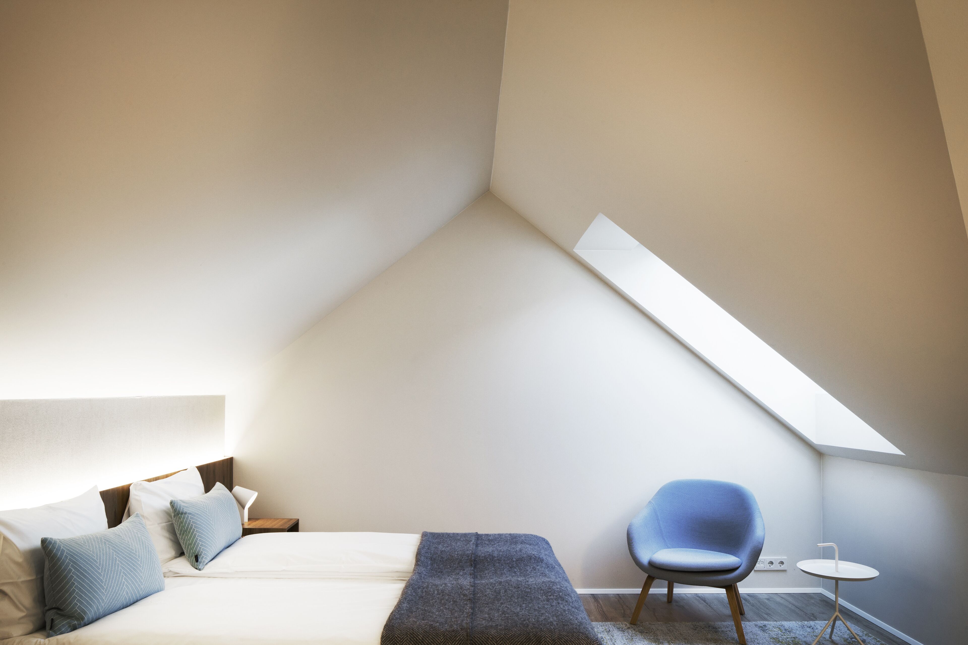Een slaapkamer met een bed, een nachtkastje, een stoel en een tafeltje.