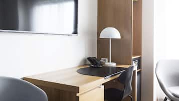 Ein moderner Arbeitsraum mit einem Holztisch, zwei Stühlen, einem Flachbildfernseher, einer Lampe und einer eingebauten Regaleinheit.