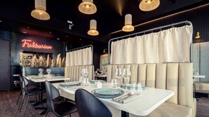 A restaurant interior with white tables, black chairs, and a neon sign reading "Fiskbarinn". - Hótel Berg (Reykjanesbær)