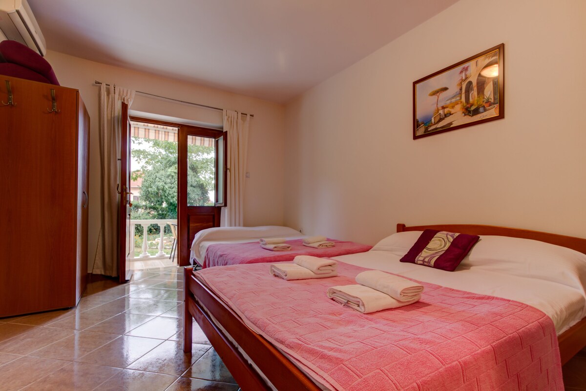 A hotel room with two beds, a balcony, and a painting on the wall.