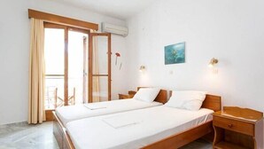 Cama doble con cabeceros de madera, una mesita de noche y una lámpara fijada a la pared.
