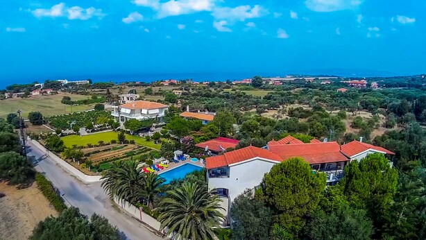 Vista aérea de una zona residencial costera con casas, piscina y una carretera.
