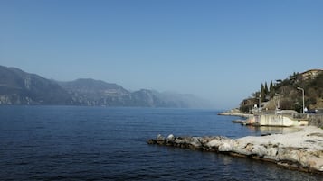Eine Küstenansicht mit ruhigem Wasser, felsiger Küste und fernen Bergen.
