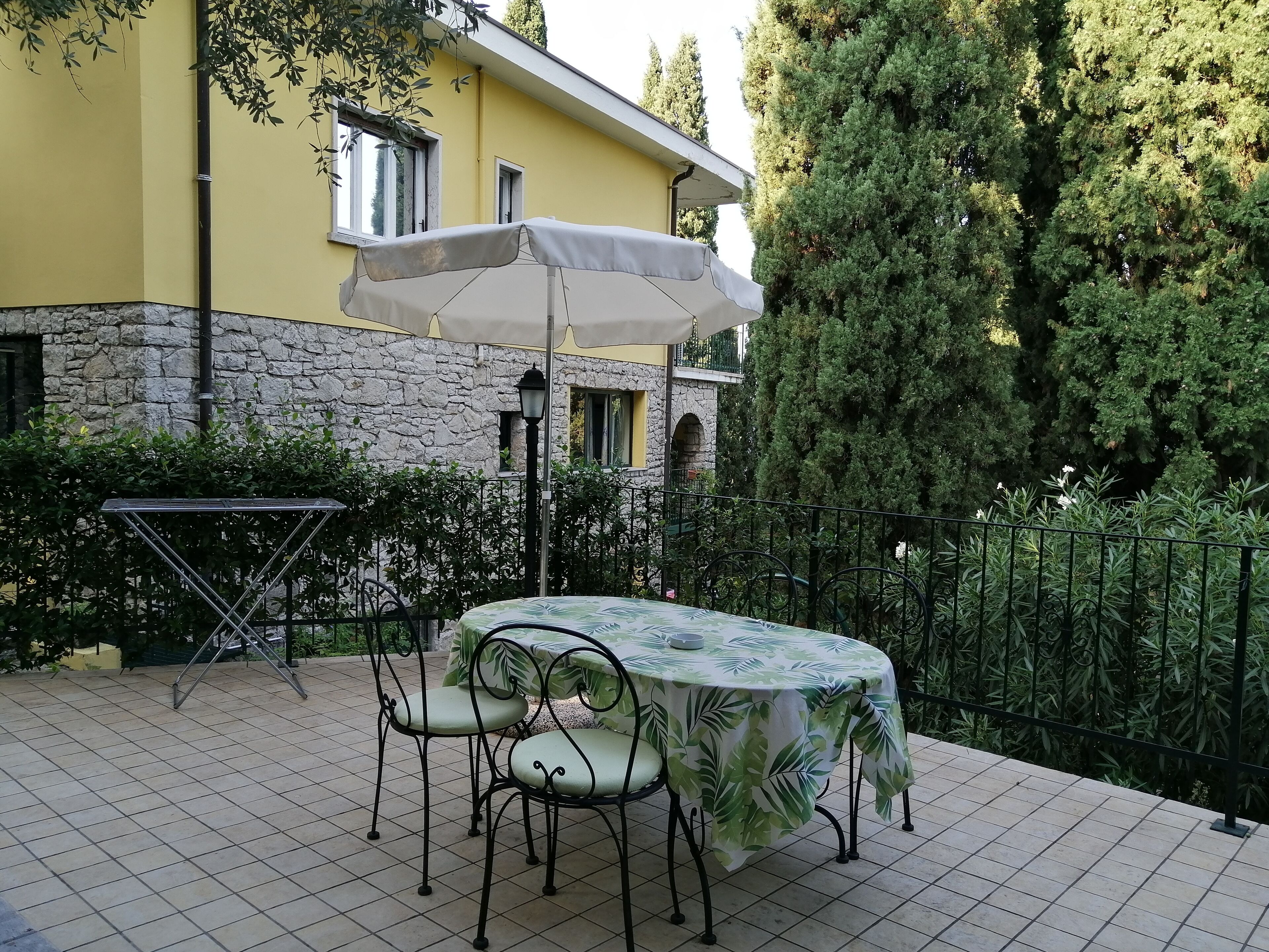 A patio with a table and chairs, an umbrella, and a stone wall.