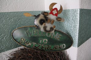 A welcome sign to Switzerland with a cow decoration. - Pension Heino (Saas Grund)