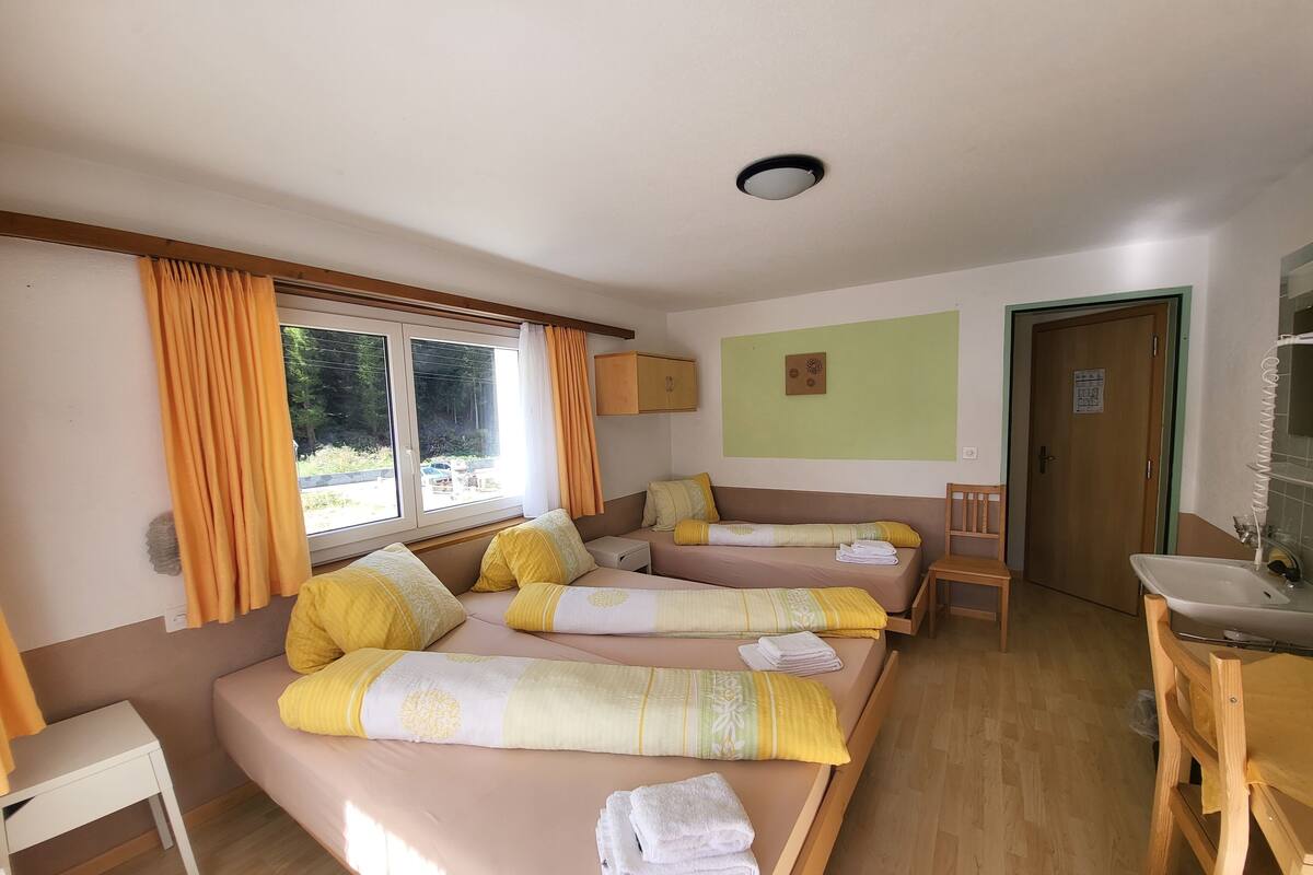 A room with two beds, a small table, a sink, and a door.
