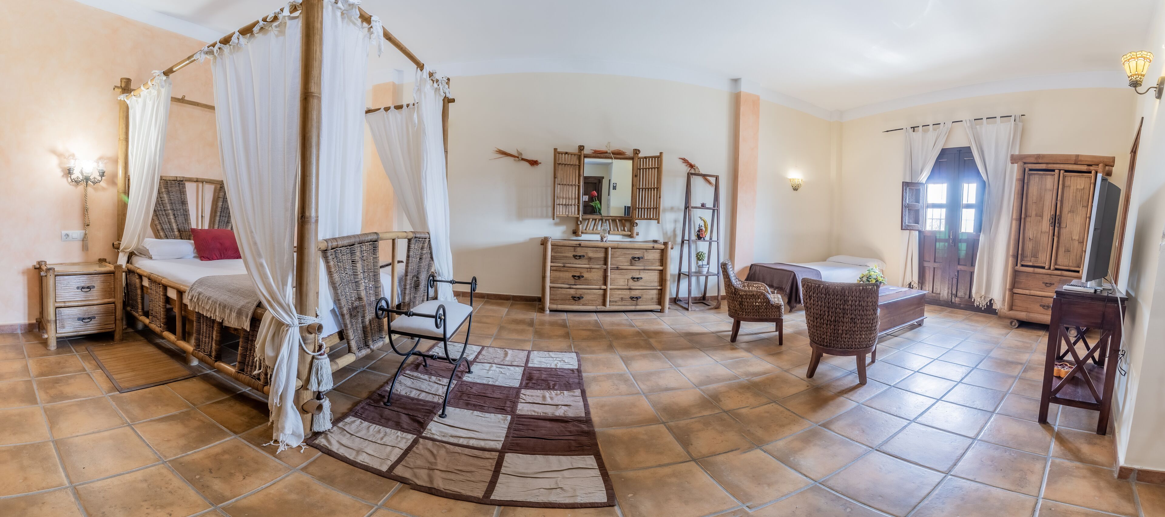 A bedroom with a four-poster bed, a wooden dresser, a chair, and a desk.