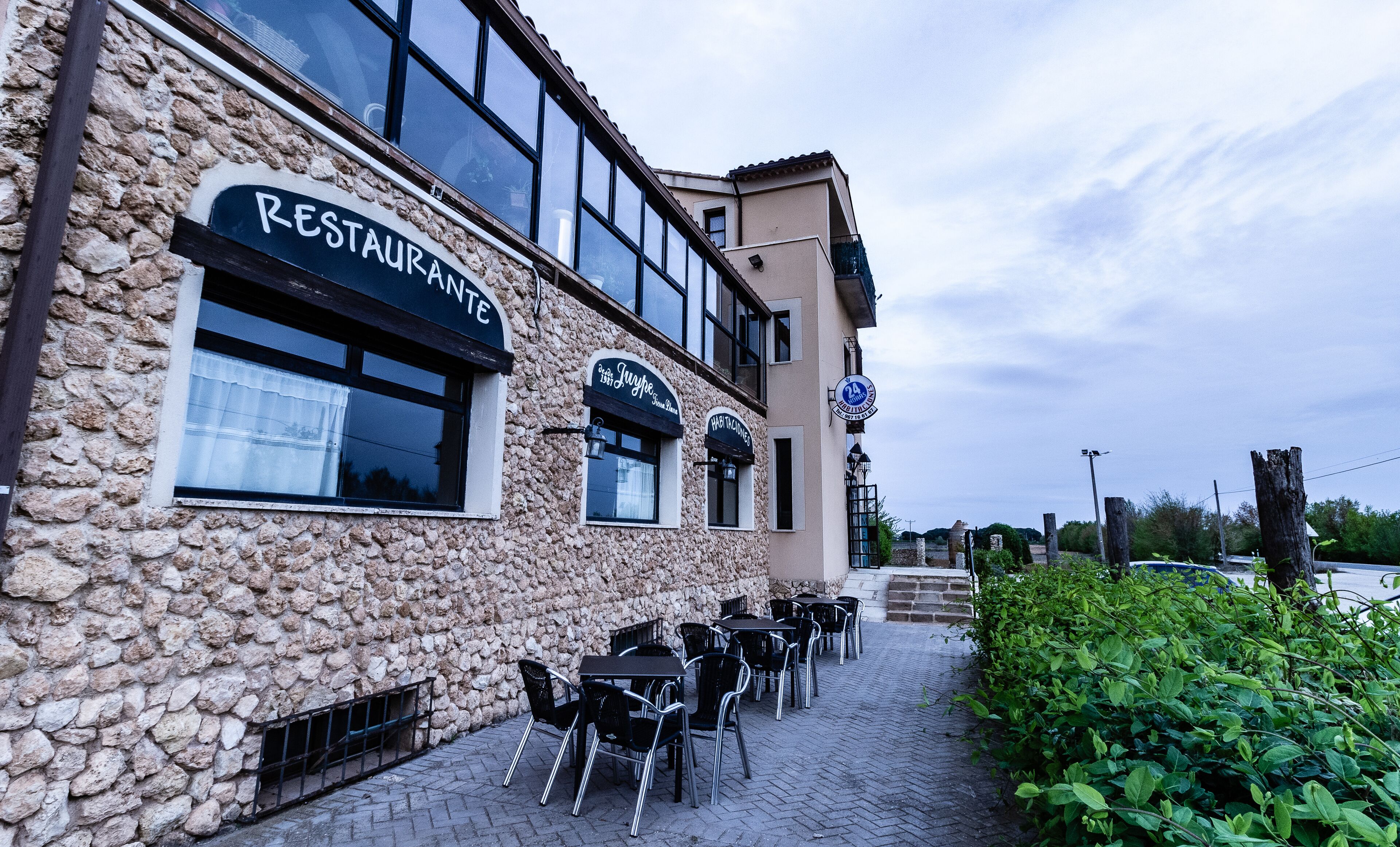 Ein Restaurant mit Außenbereich, Steinmauern und mehreren Fenstern.