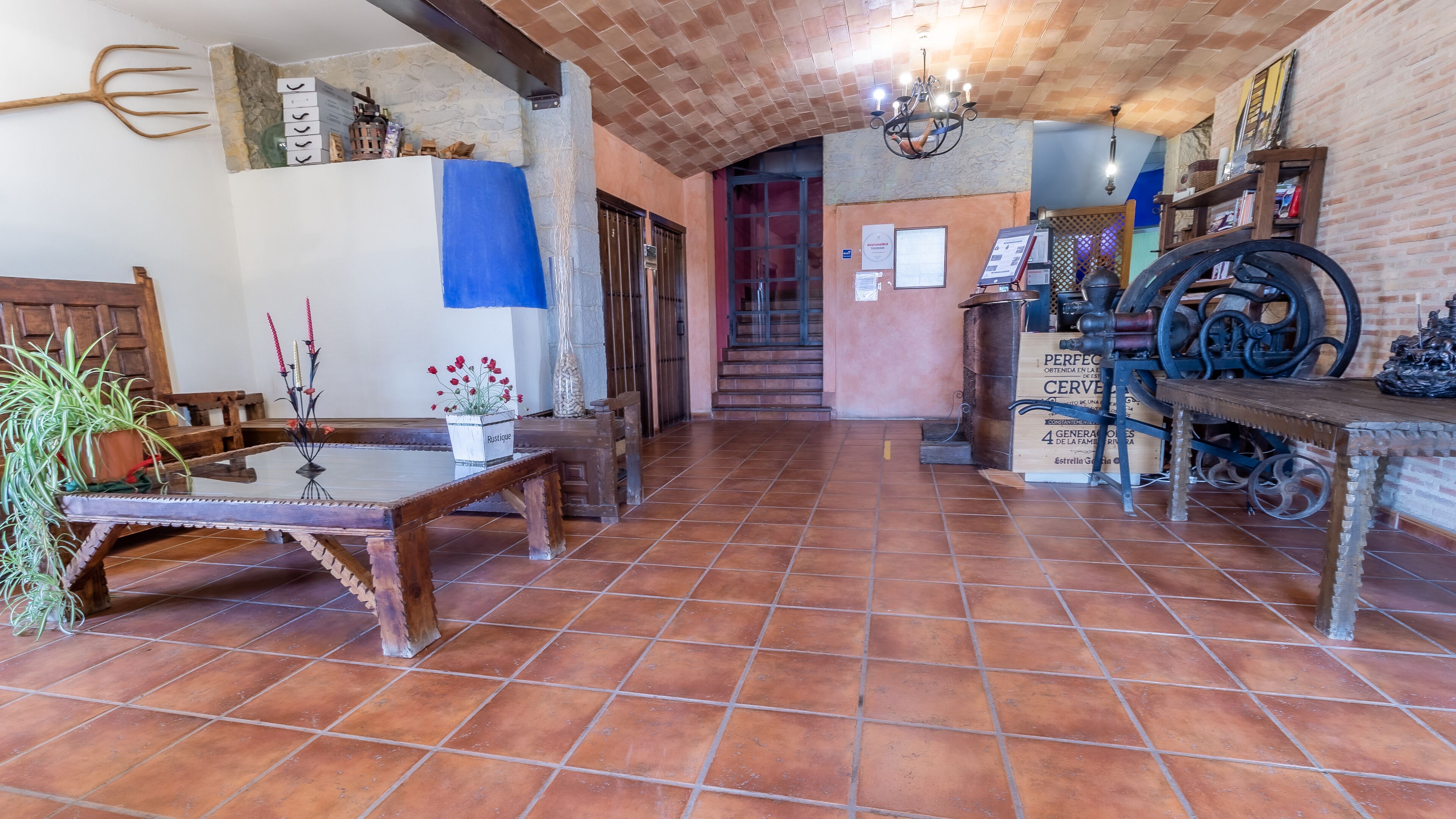 A rustic interior with a tiled floor, wooden furniture, and a staircase leading to an upper level.
