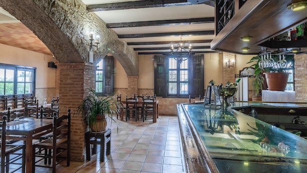 A restaurant with exposed brick walls, wooden beams, and a bar area with a glass counter. - Hosteria Tierrallana by Juypehotel (El Provencio)