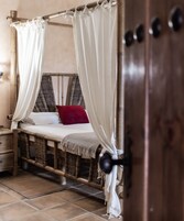 Una habitación con cama, mesita de noche y puerta de madera.