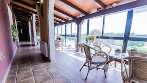 A covered outdoor area with tiled flooring, wicker furniture, and potted plants. - Hosteria Tierrallana by Juypehotel (El Provencio)