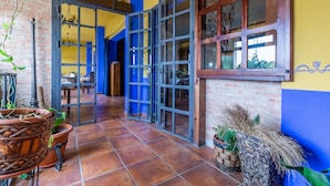 A spacious hallway with tiled flooring, a brick wall, and a blue door leading to another room. - Hosteria Tierrallana by Juypehotel (El Provencio)