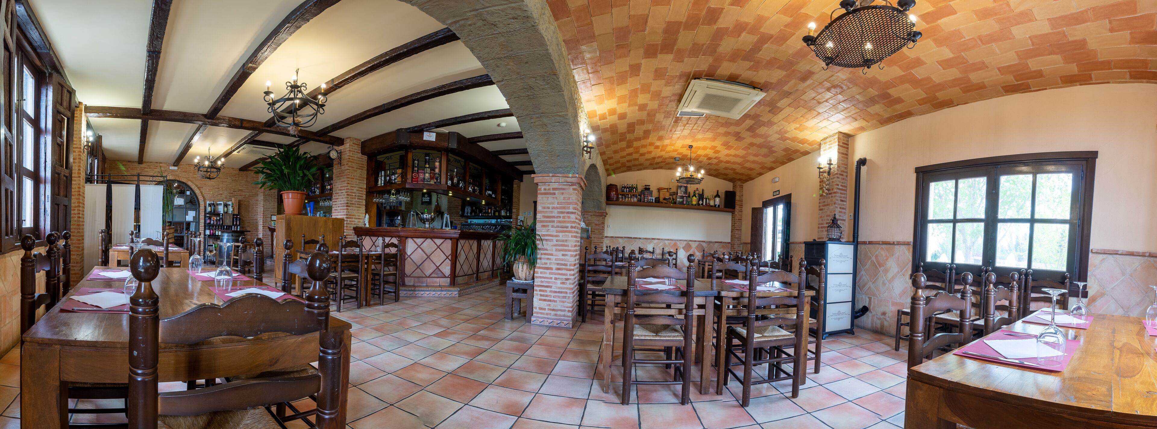 Un restaurante con techos altos, paredes de ladrillo visto y mobiliario de madera.