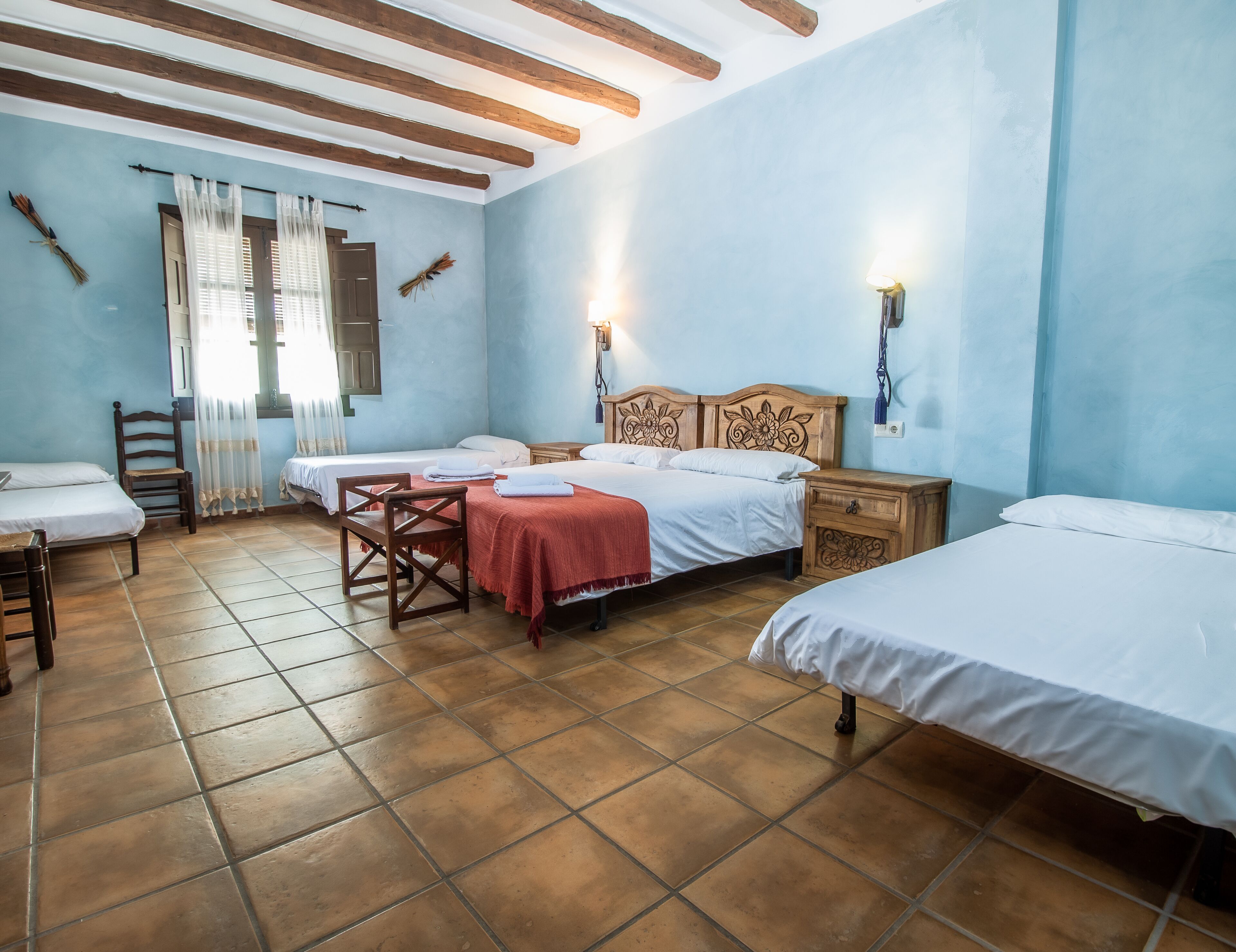 A room with two beds, a wooden chair, a small table, and a nightstand.