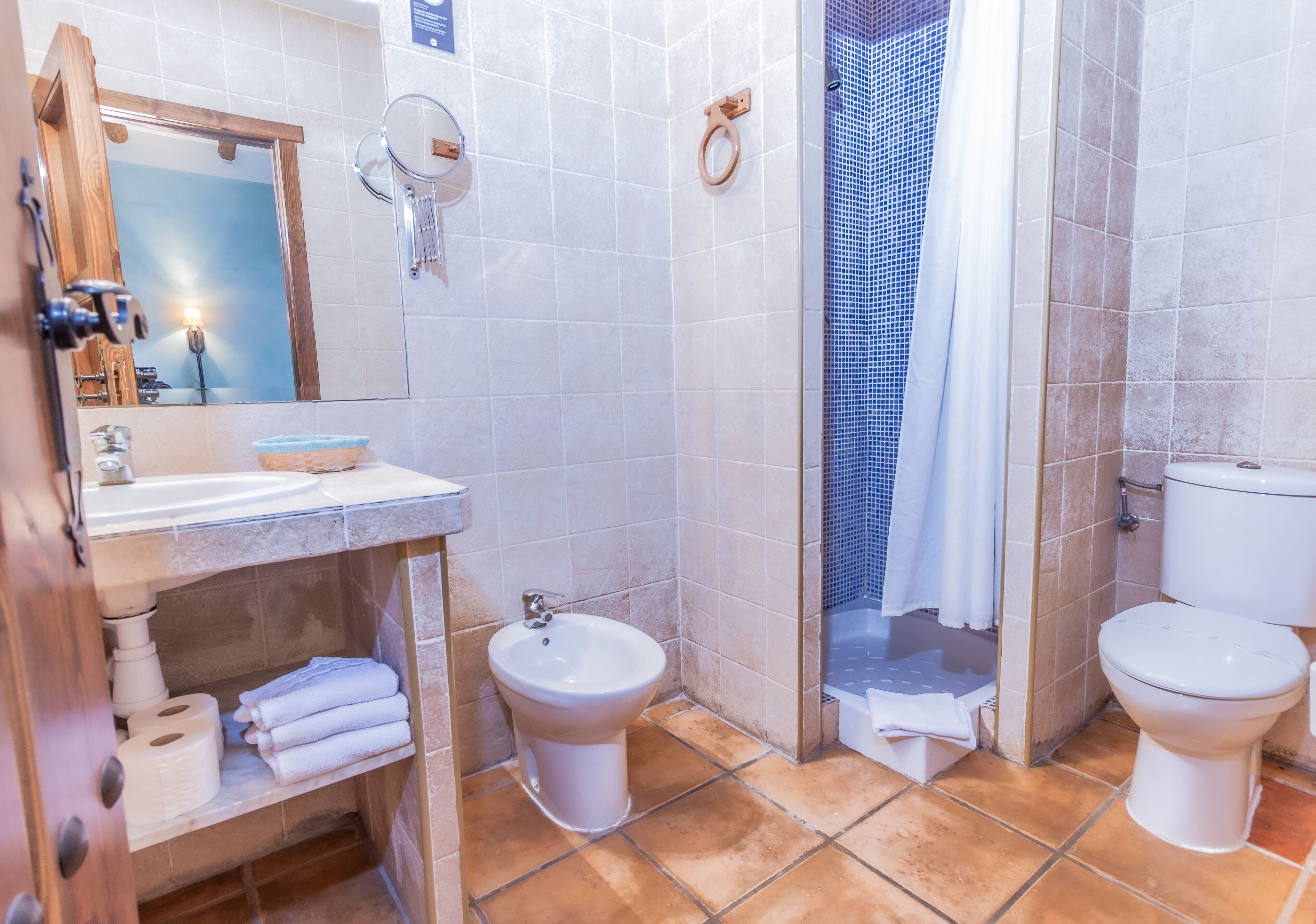 A bathroom with a sink, bidet, toilet, and shower.