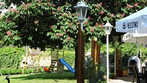 A garden with a wooden play structure, a slide, and a pergola with climbing plants. - Landhotel Combecher (Neukirchen)