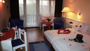 A hotel room with a bed, a desk, a chair, a nightstand, and a lamp. - Landhotel Combecher (Neukirchen)
