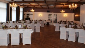 A banquet hall with multiple round tables set for events, chandeliers, and a wooden floor. - Landhotel Combecher (Neukirchen)