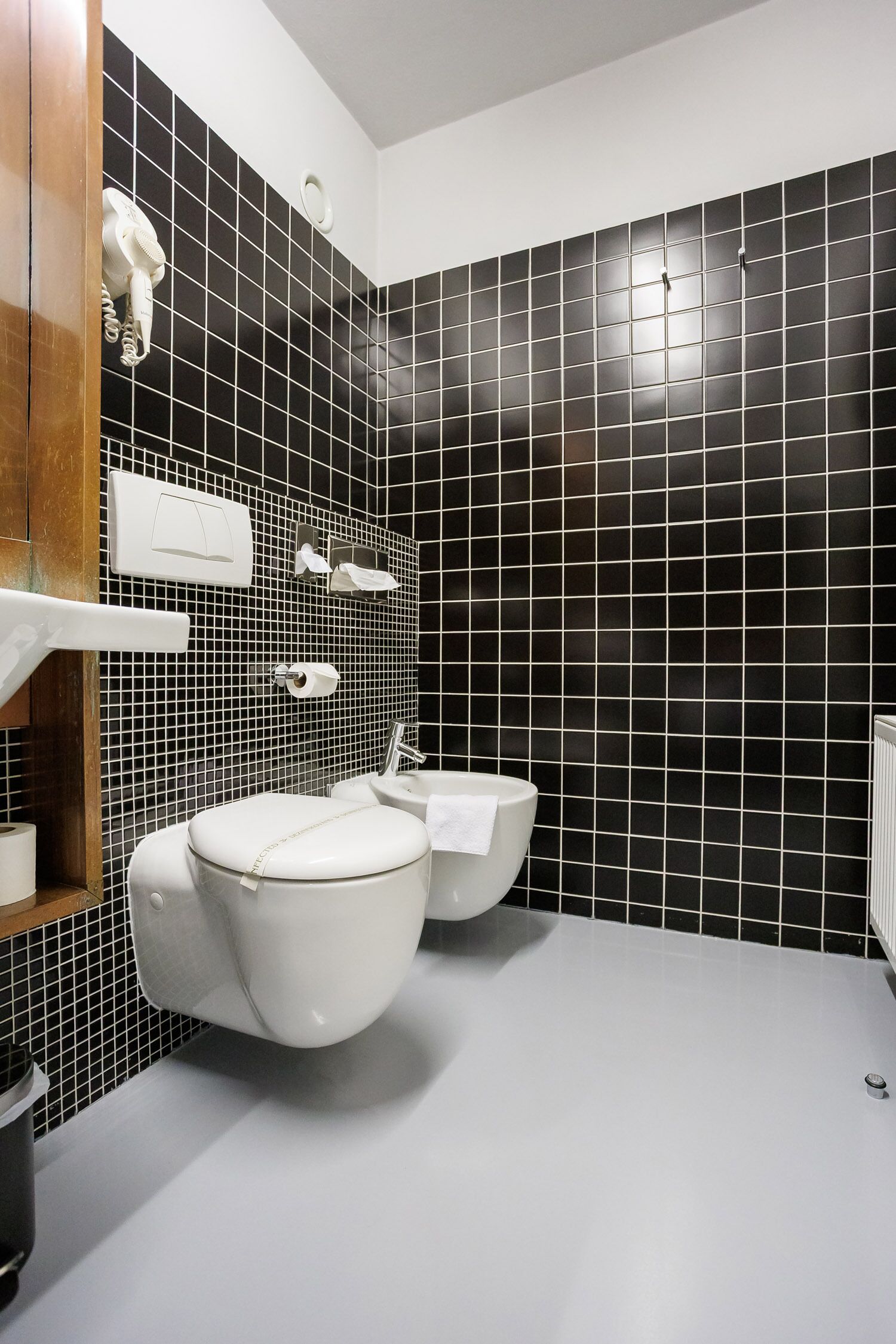 A modern bathroom with a toilet, bidet, and a white sink.