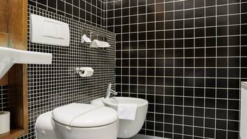 A modern bathroom with a toilet, bidet, and a white sink.