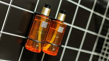 Two bottles of perfume hanging on a tiled wall.